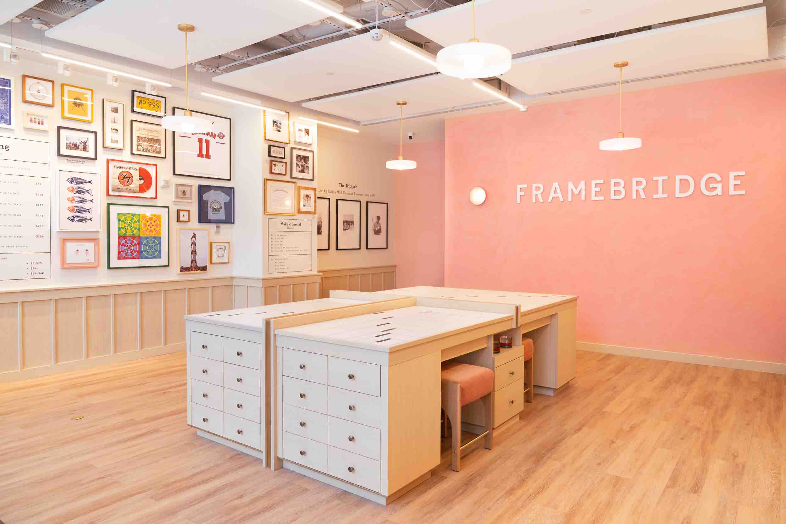 A Framebridge store with pink walls, consultation tables, and a display of framed art and keepsakes