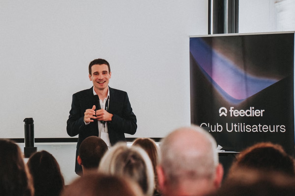 François Forest speaking in front of an audience beside a Feedier Club Utilisateurs banner