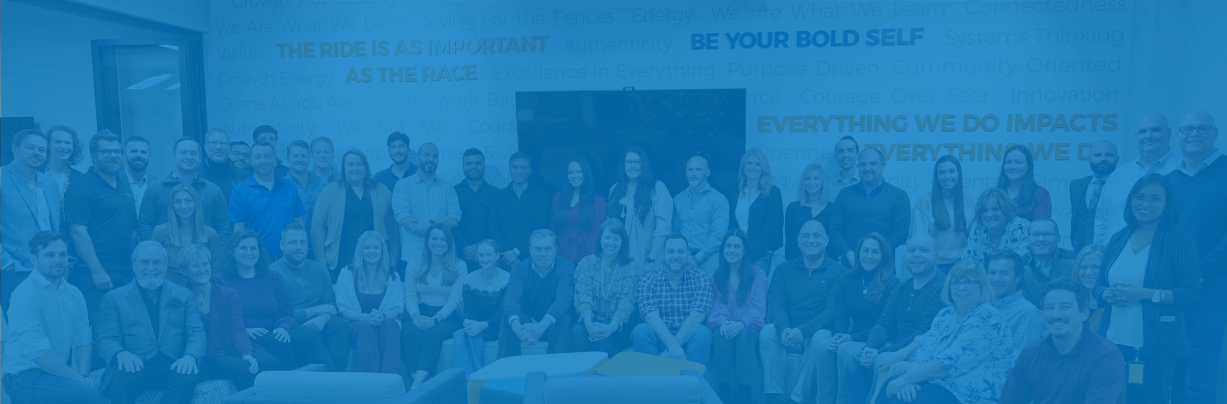 FranConnect team gathered in an office beneath company values on the wall