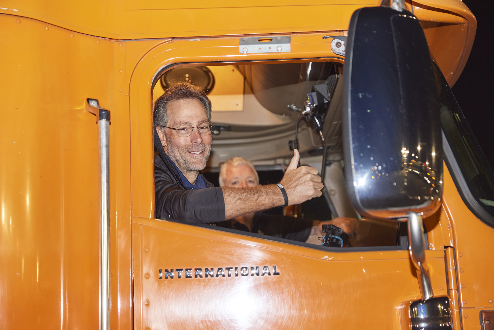 Frank Lonegro gives a thumbs-up from the passenger side of Jeff Stone's orange truck
