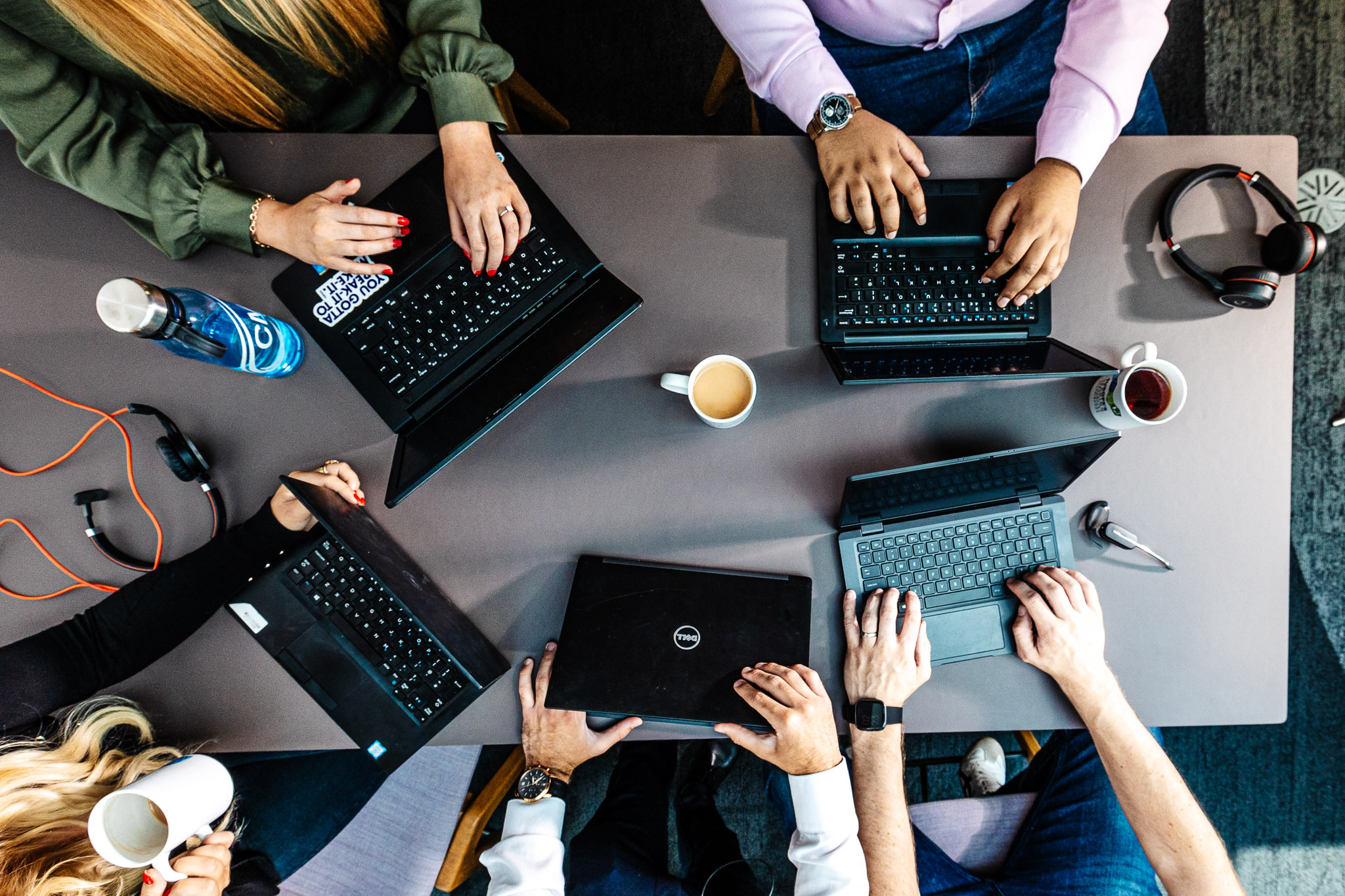 An overhead view of CMS colleagues working around a table with laptops and drinks