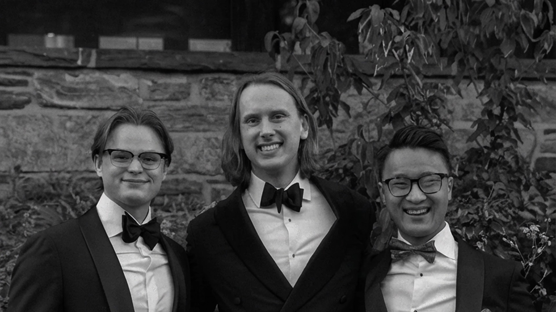 Fred Havemeyer stands smiling in formalwear with two friends