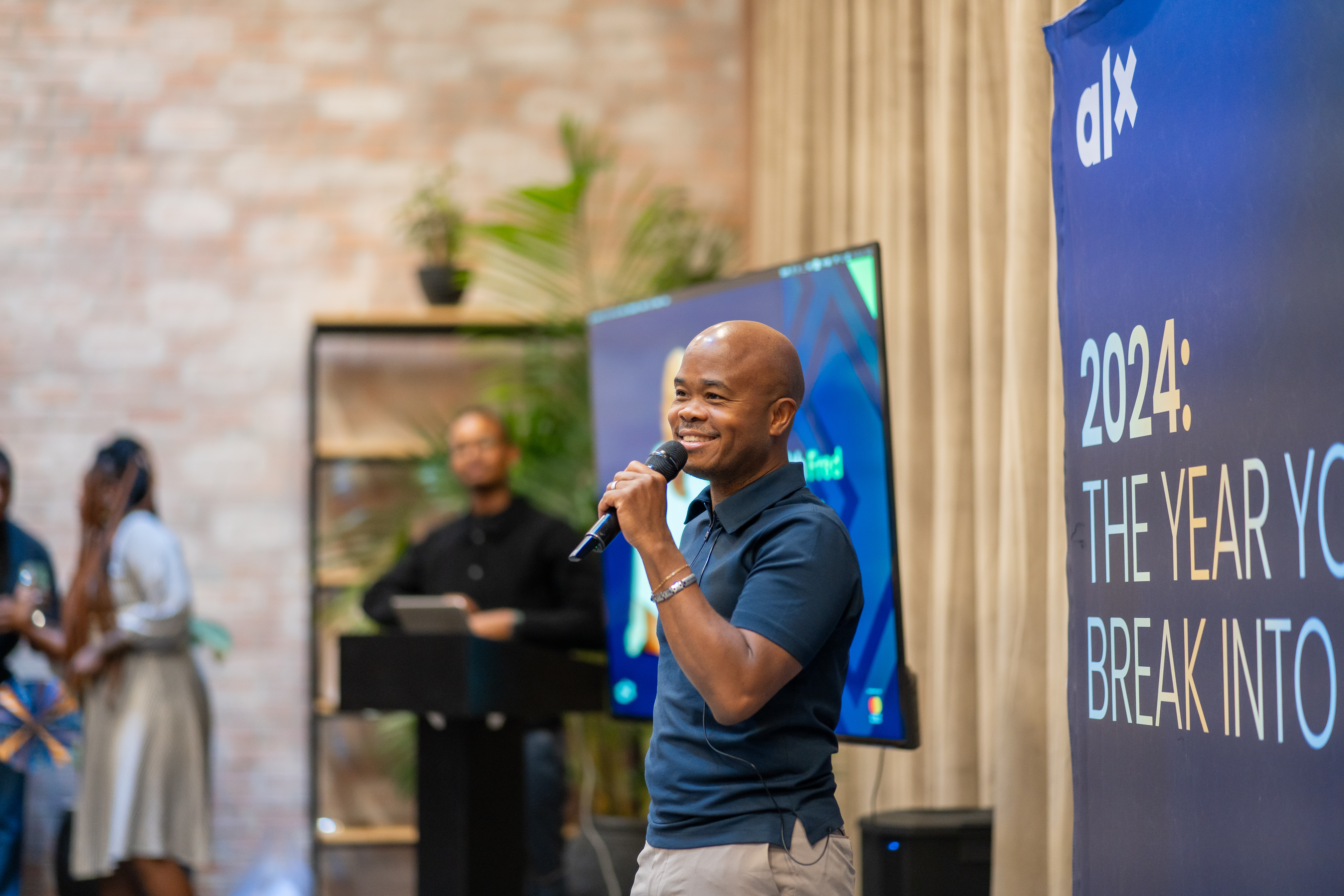 Fred Swaniker speaking into a microphone at an ALX learners event