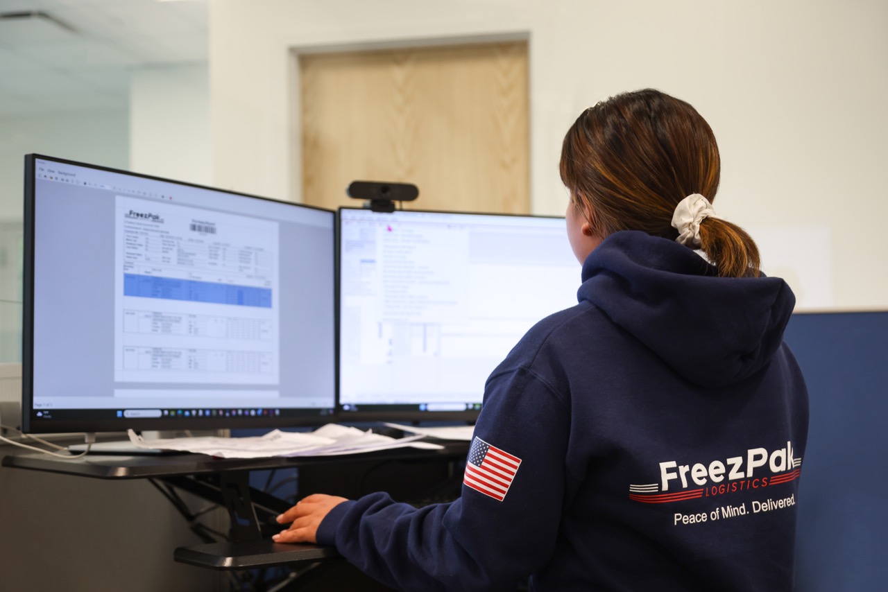 FreezPak operations employee working at two computer monitors