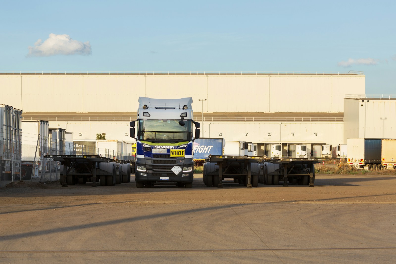Semi trailers parked in a freight yard outside a warehouse