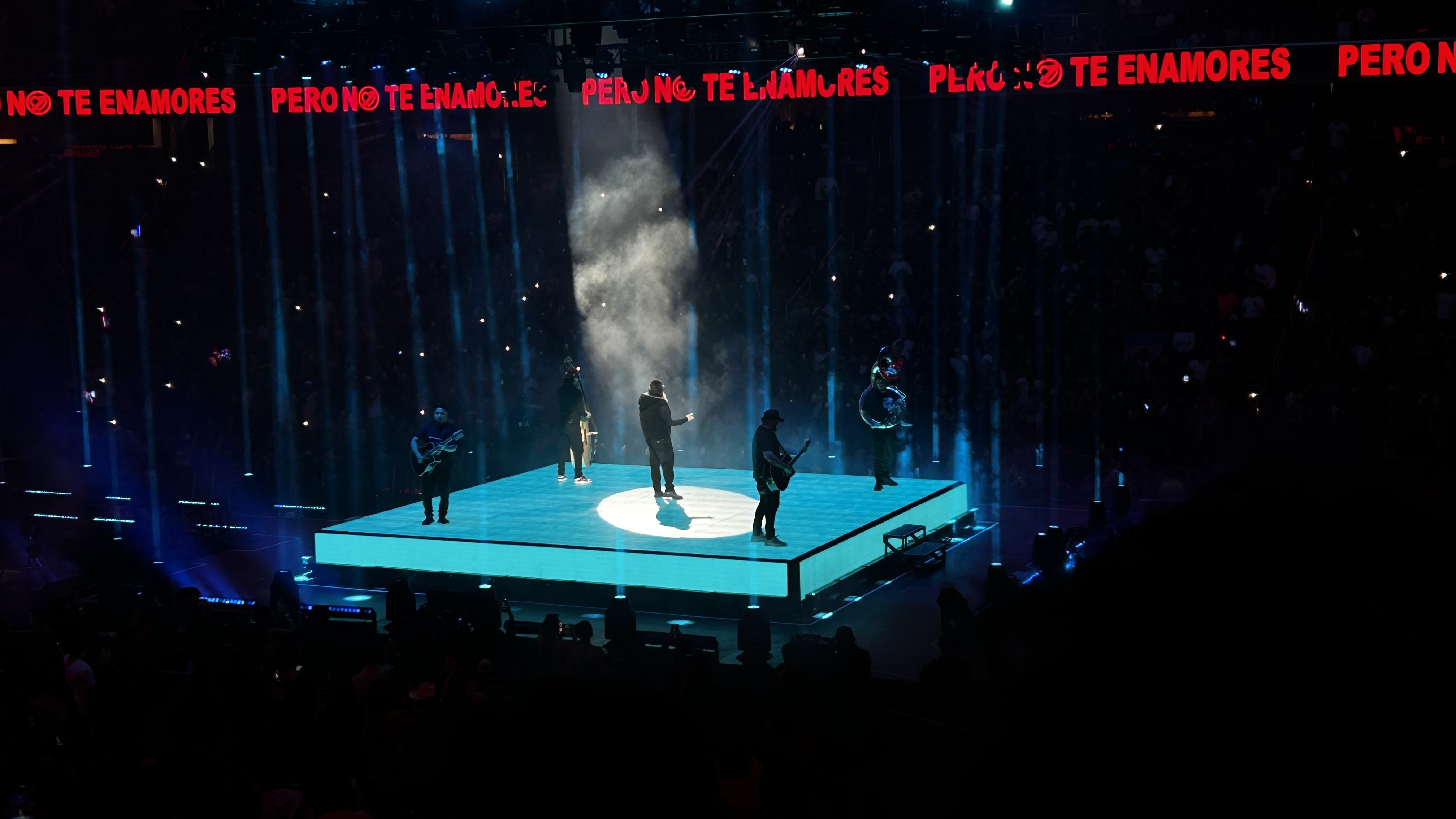 Fuerza Regida performing on a bright square stage inside Capital One Arena