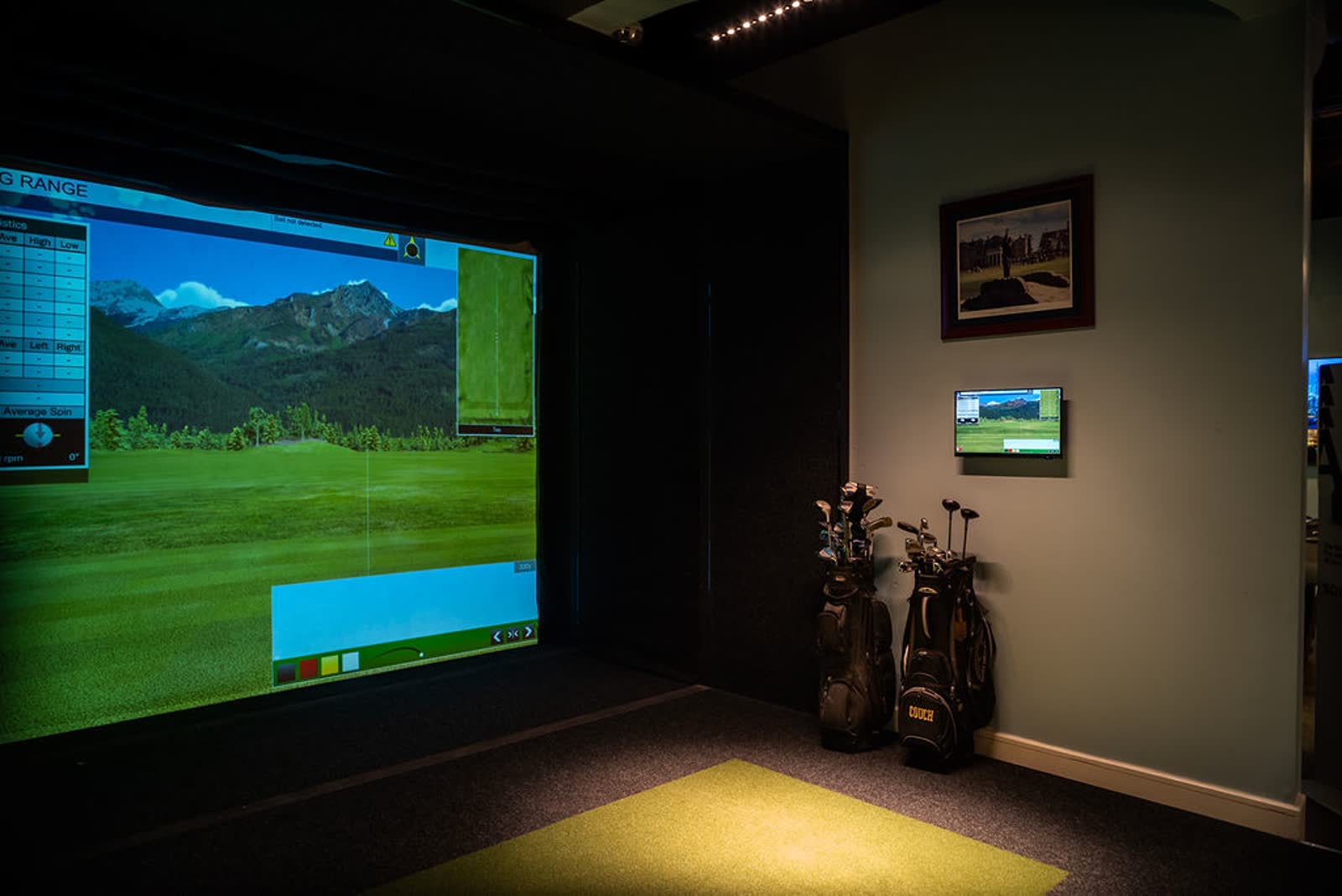 Custom indoor golf simulator with a large projection screen and hitting mat