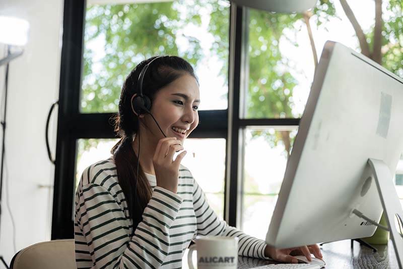 A headset-wearing worker taking a call at a home computer