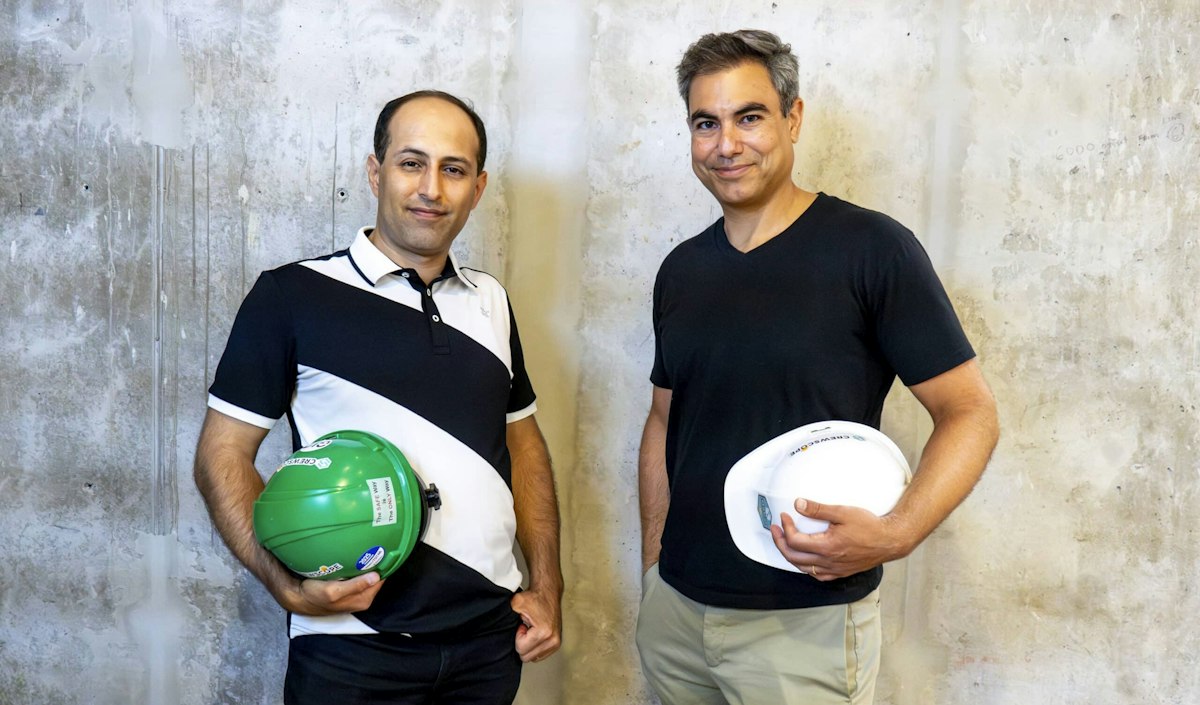 Two members of Crewscope's team holding green and white construction hard hats