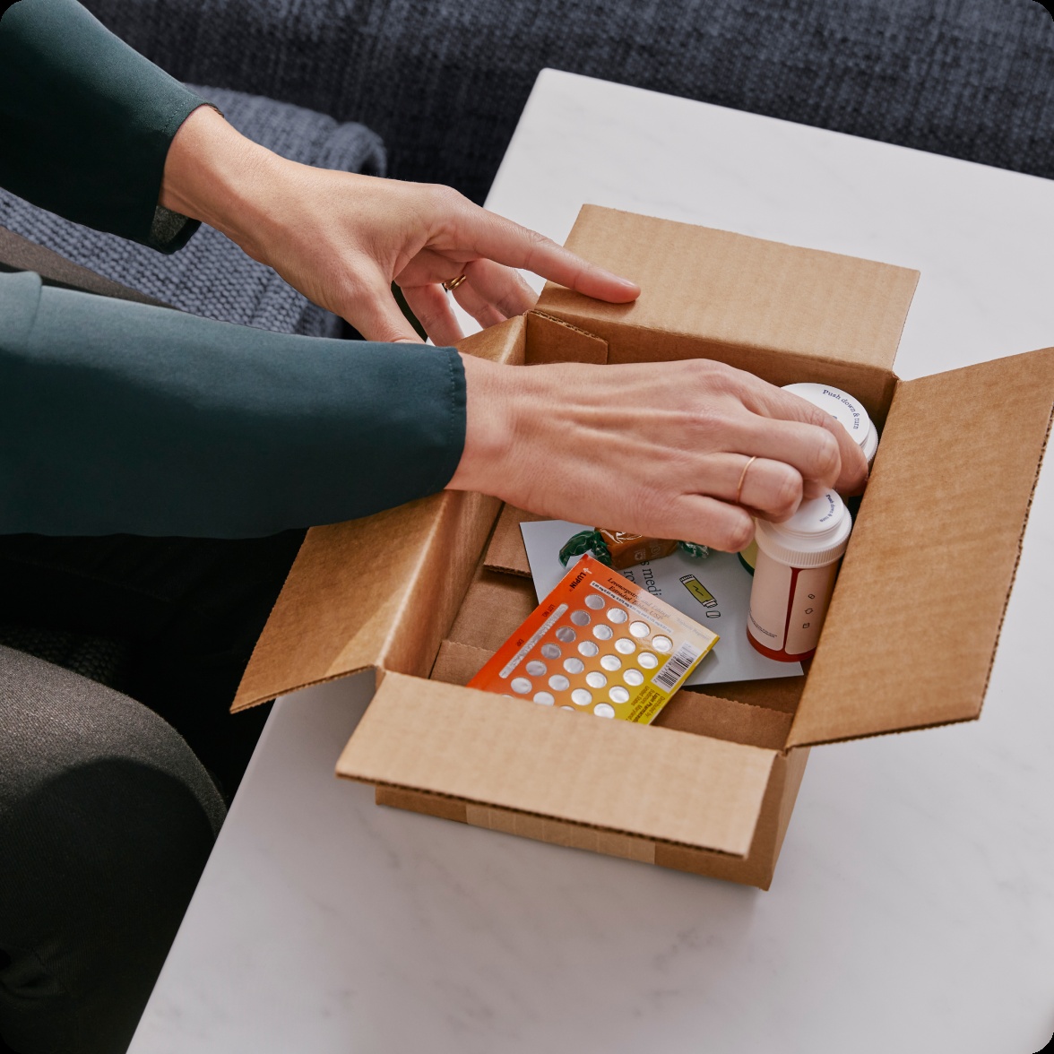 Hands unpacking prescription bottles and medication from a pharmacy delivery box