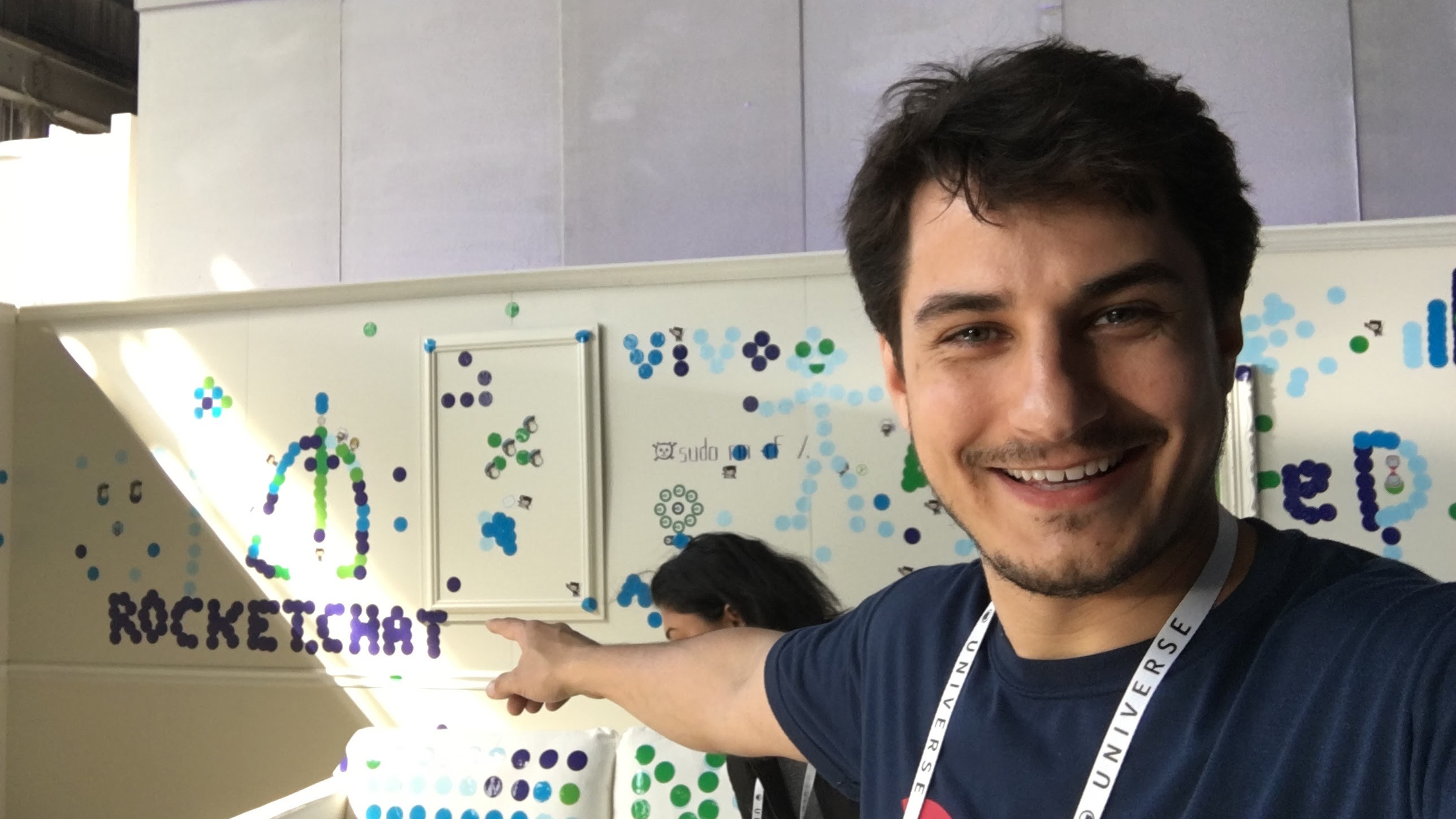 Gabriel Engel pointing to Rocket.Chat lettering made from stickers