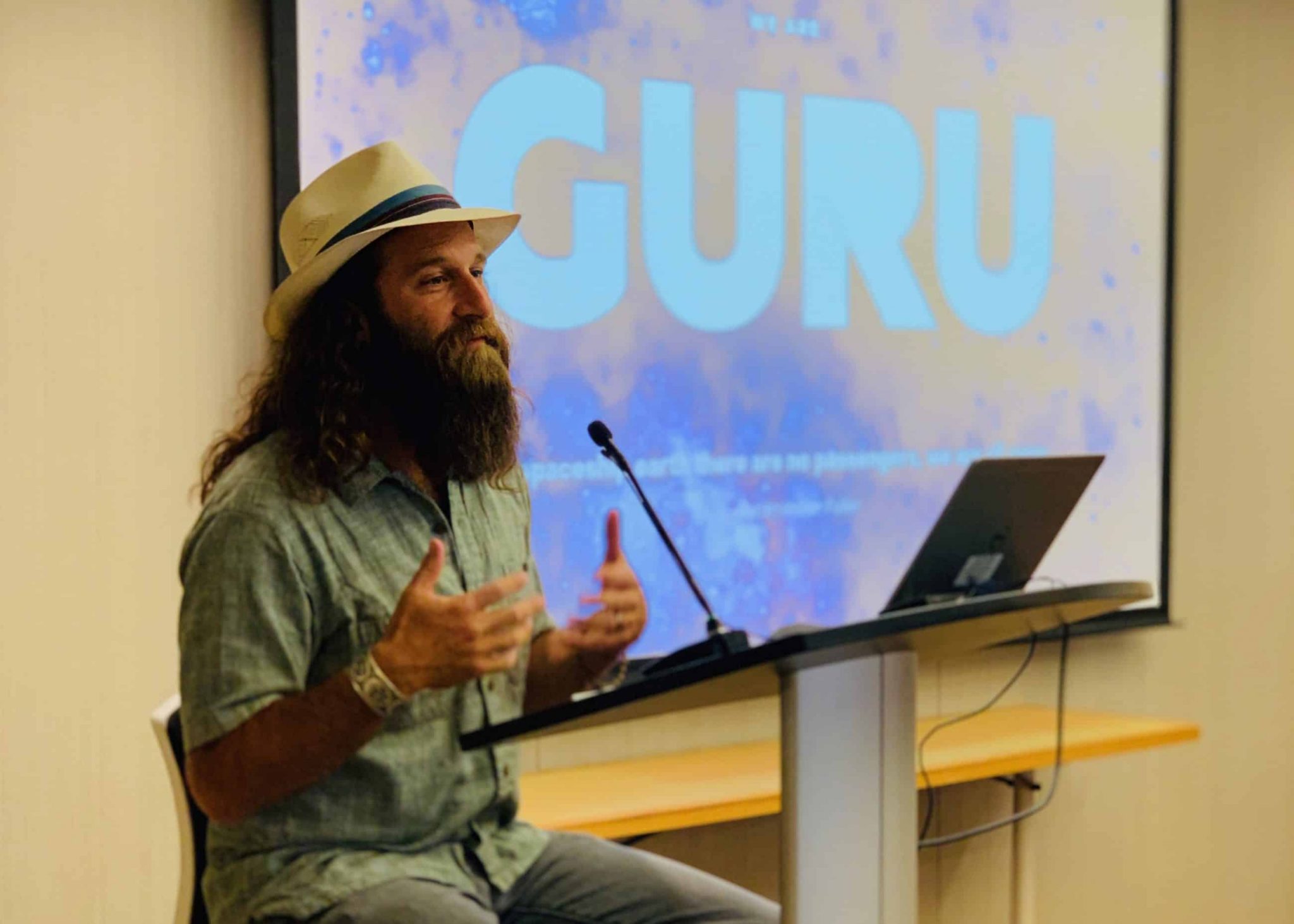 Gagan Levy, wearing a hat, speaks at a lectern during a natural-products climate forum.
