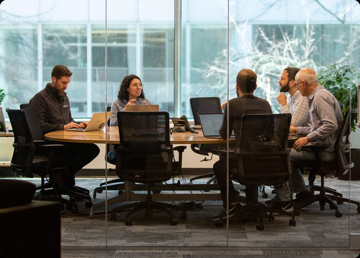 Galois colleagues working around a table in a glass-walled meeting room