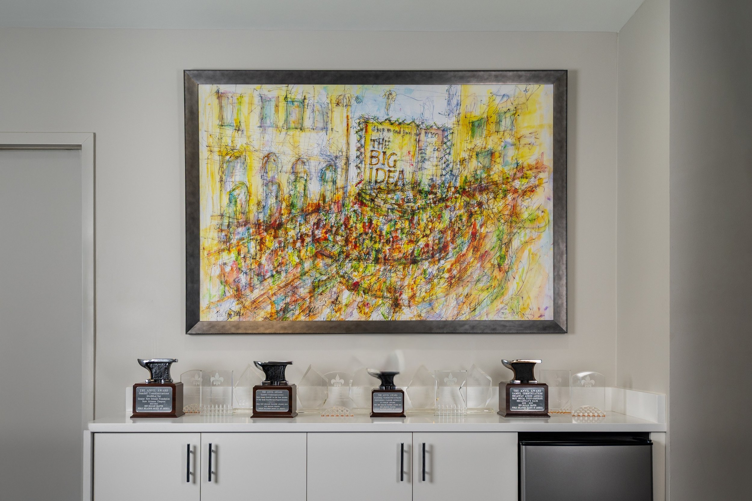 A colorful New Orleans artwork above a shelf filled with Gambel Communications awards