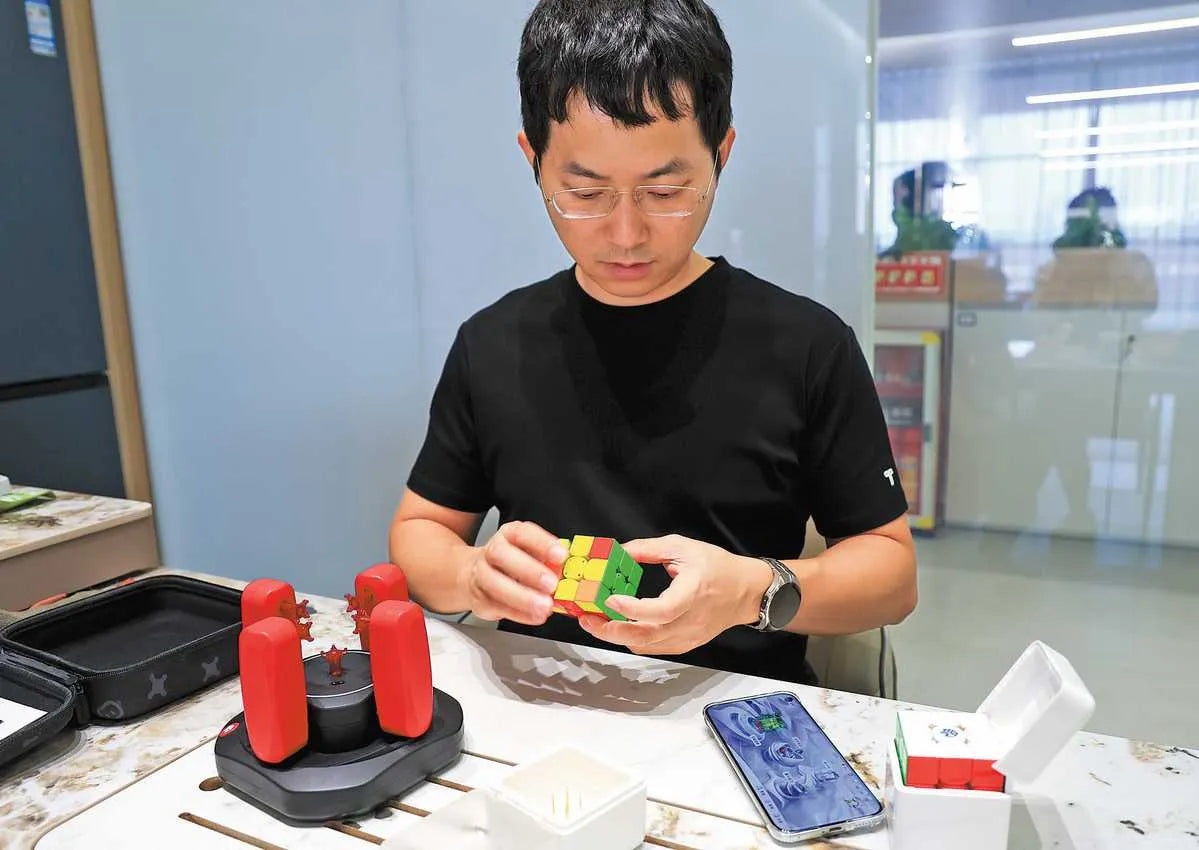 Jiang Ganyuan demonstrating a cube at a table