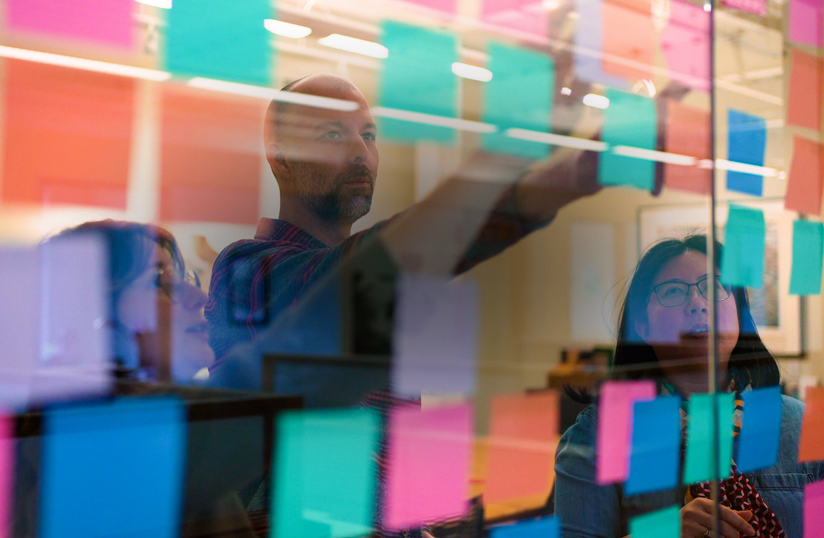 Gard team members organizing a project with brightly colored notes on glass