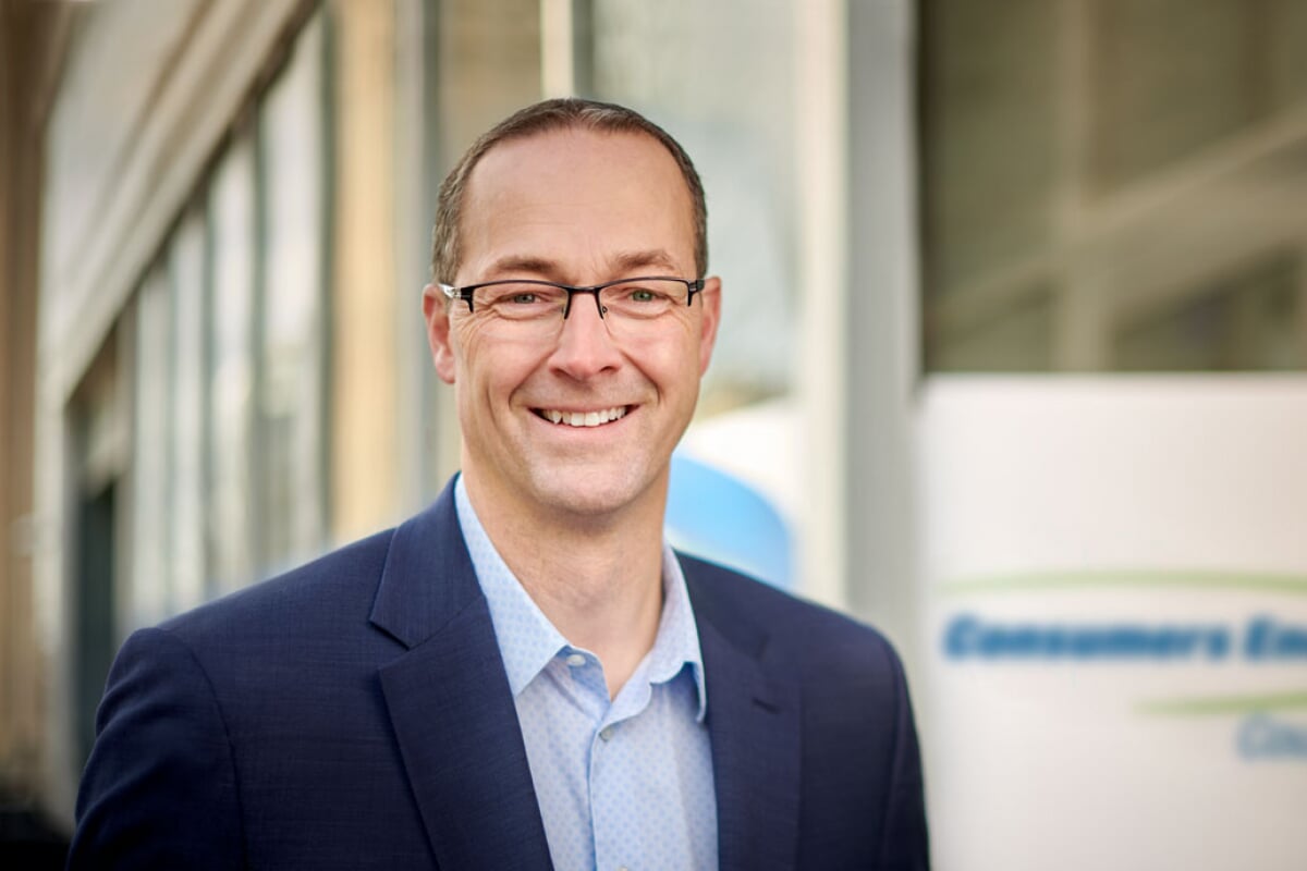 Garrick Rochow outside a Consumers Energy building, wearing a blue jacket and open-collar shirt