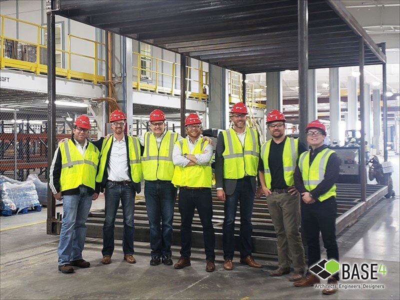 Seven BASE4 colleagues in hard hats and safety vests at the Z Modular factory, with Garry Vermaas third from left