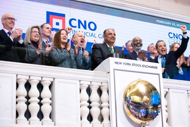 Gary Bhojwani, wearing a green tie at center, with cheering CNO colleagues at the New York Stock Exchange opening bell