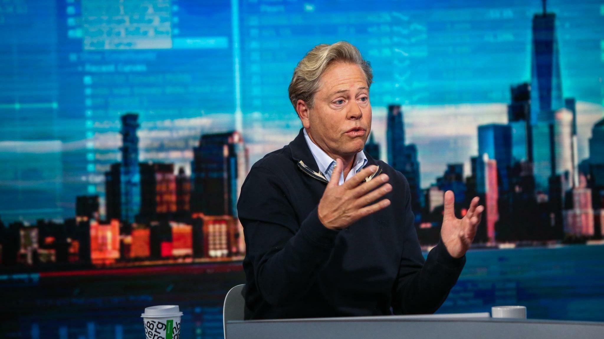 Gary Burnison gesturing during a television interview with a New York skyline behind him