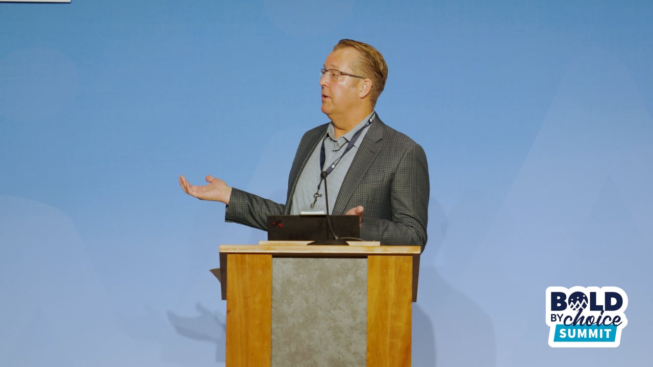Gary Larson speaking behind a lectern at the Bold by Choice Summit
