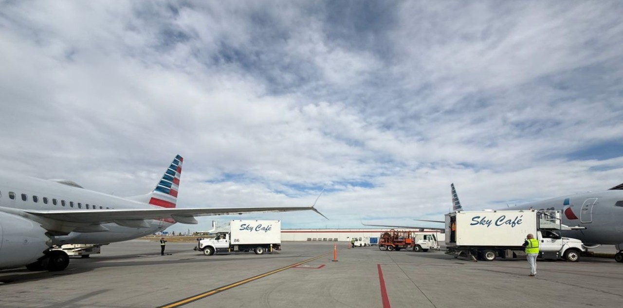 Sky Café catering trucks positioned beside American Airlines aircraft on an airport ramp.