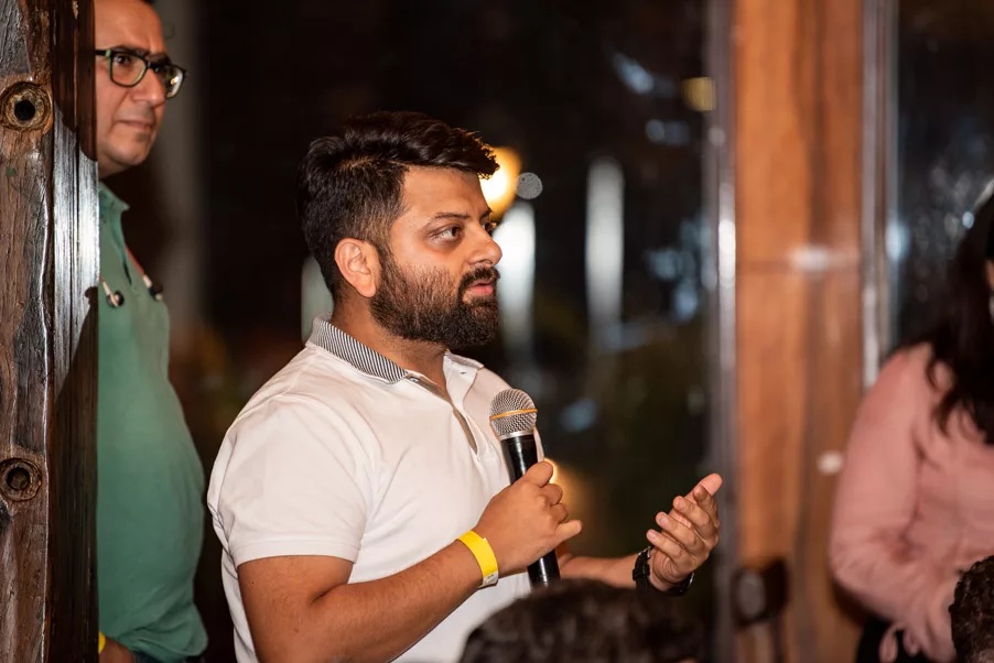 Gautam Ghai holding a microphone while addressing a startup gathering