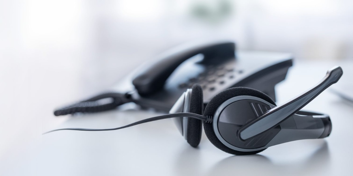 A telephone headset resting beside a desk phone in GCC7’s published recruitment image