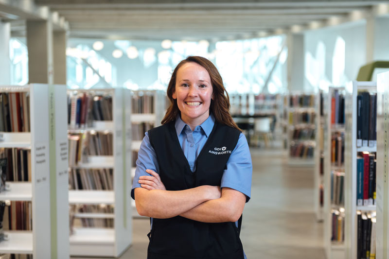 A GDI Ainsworth employee standing in a bright library