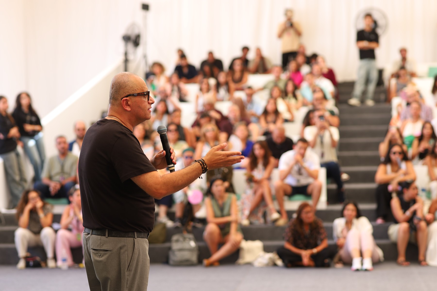 Adly Thoma speaking into a microphone before an audience at a Gemini CinemaTech event