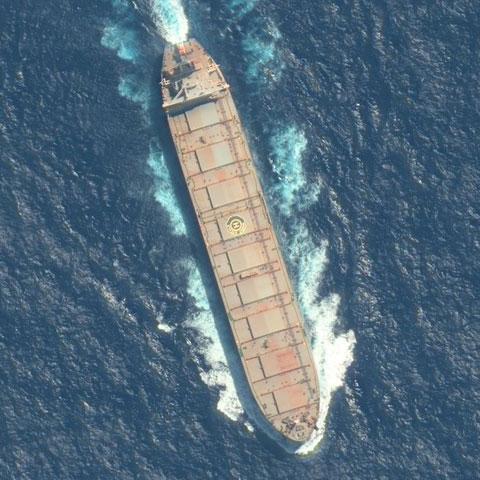 Satellite view of a cargo ship at sea, showing its deck and wake