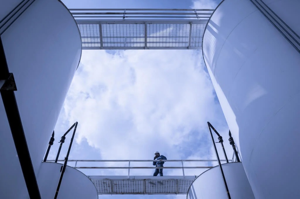 A worker on a walkway between large industrial structures in a photograph published by GenOn