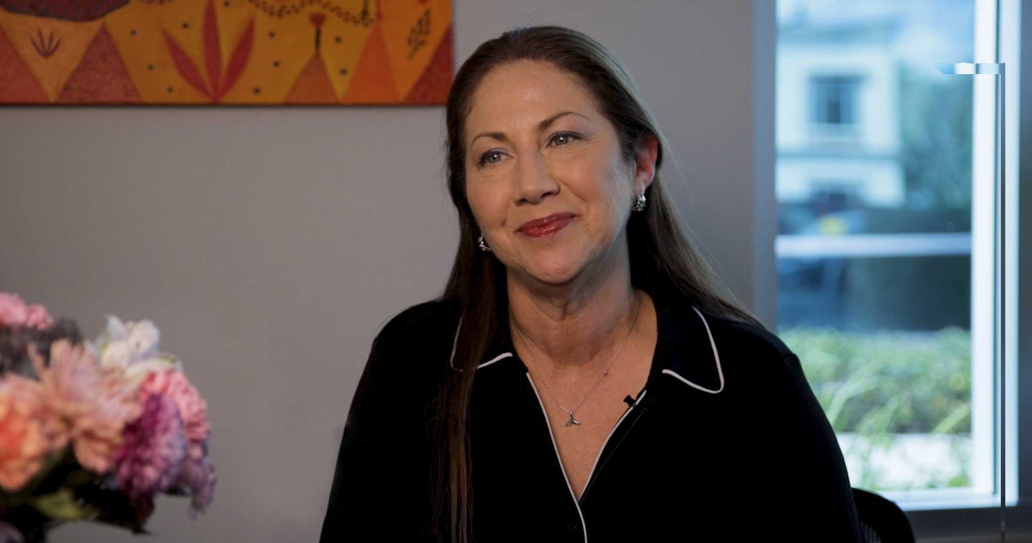 Genoveva Arellano speaks during a filmed interview in an office overlooking a courtyard.