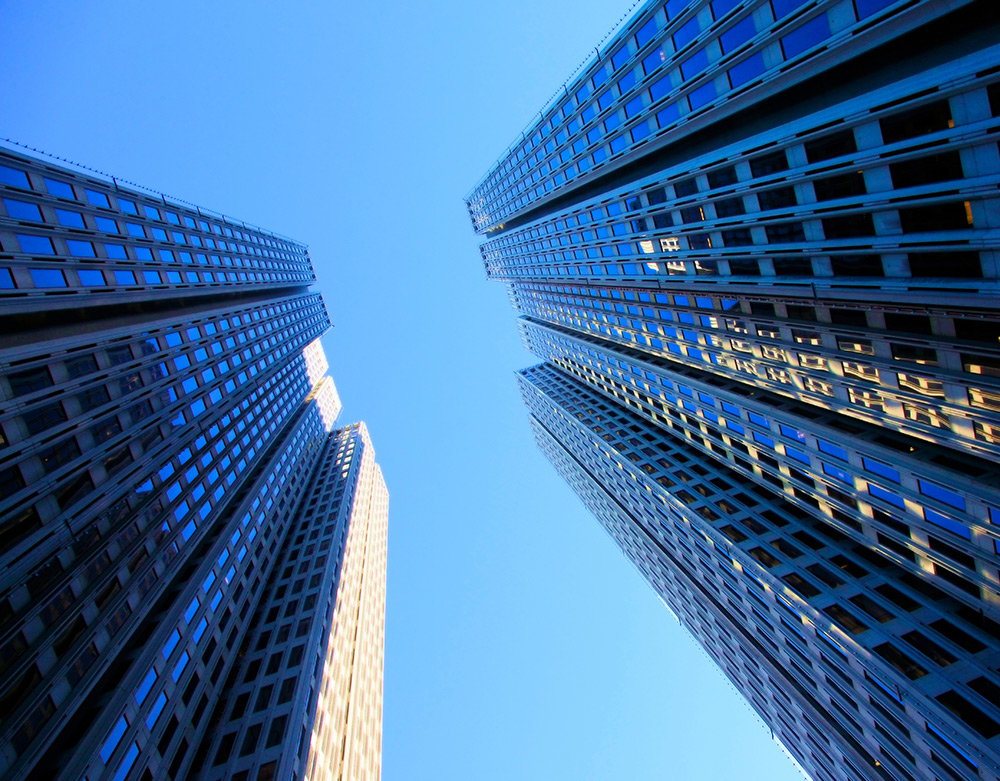 Looking upward between San Francisco towers toward a bright blue sky