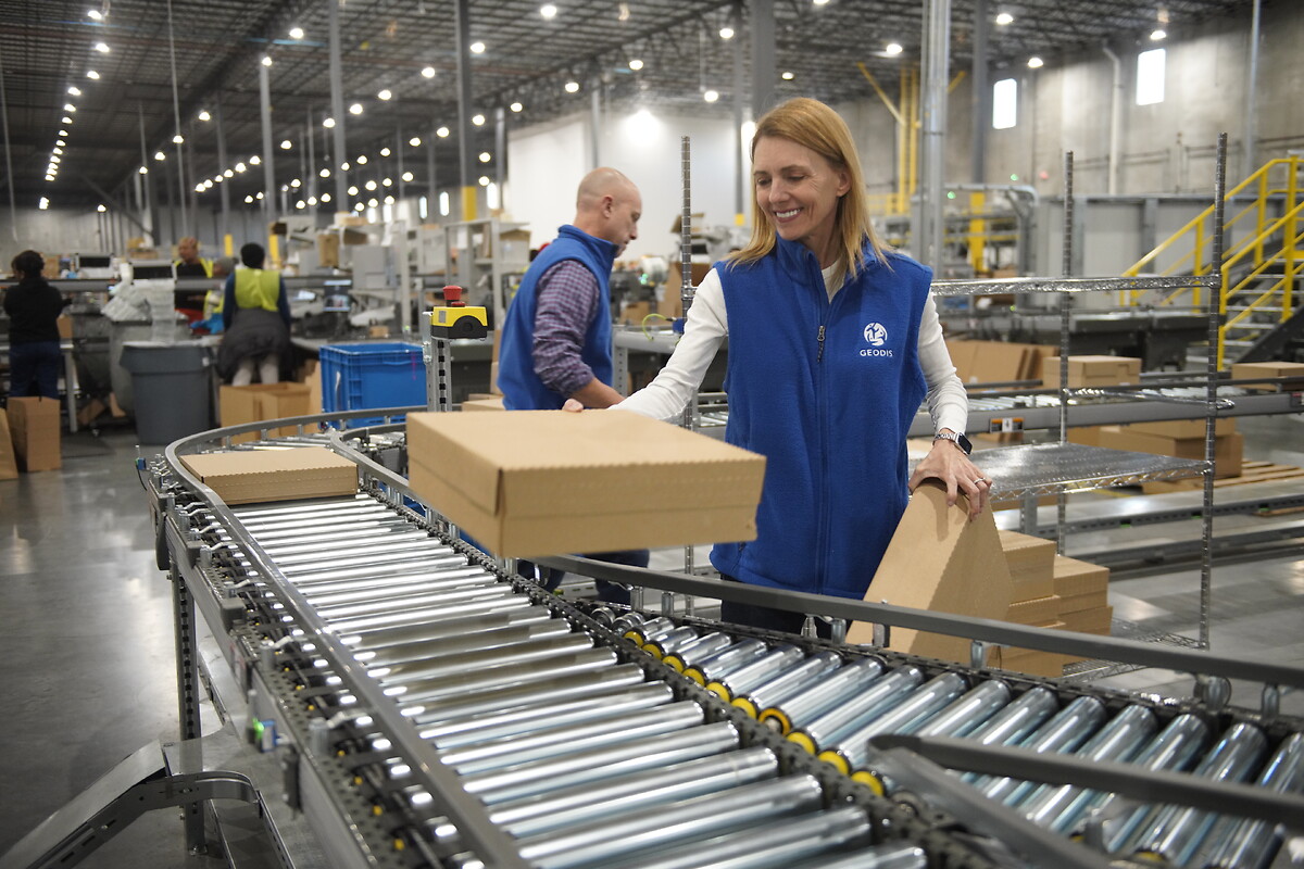GEODIS warehouse employee handling cartons beside a conveyor