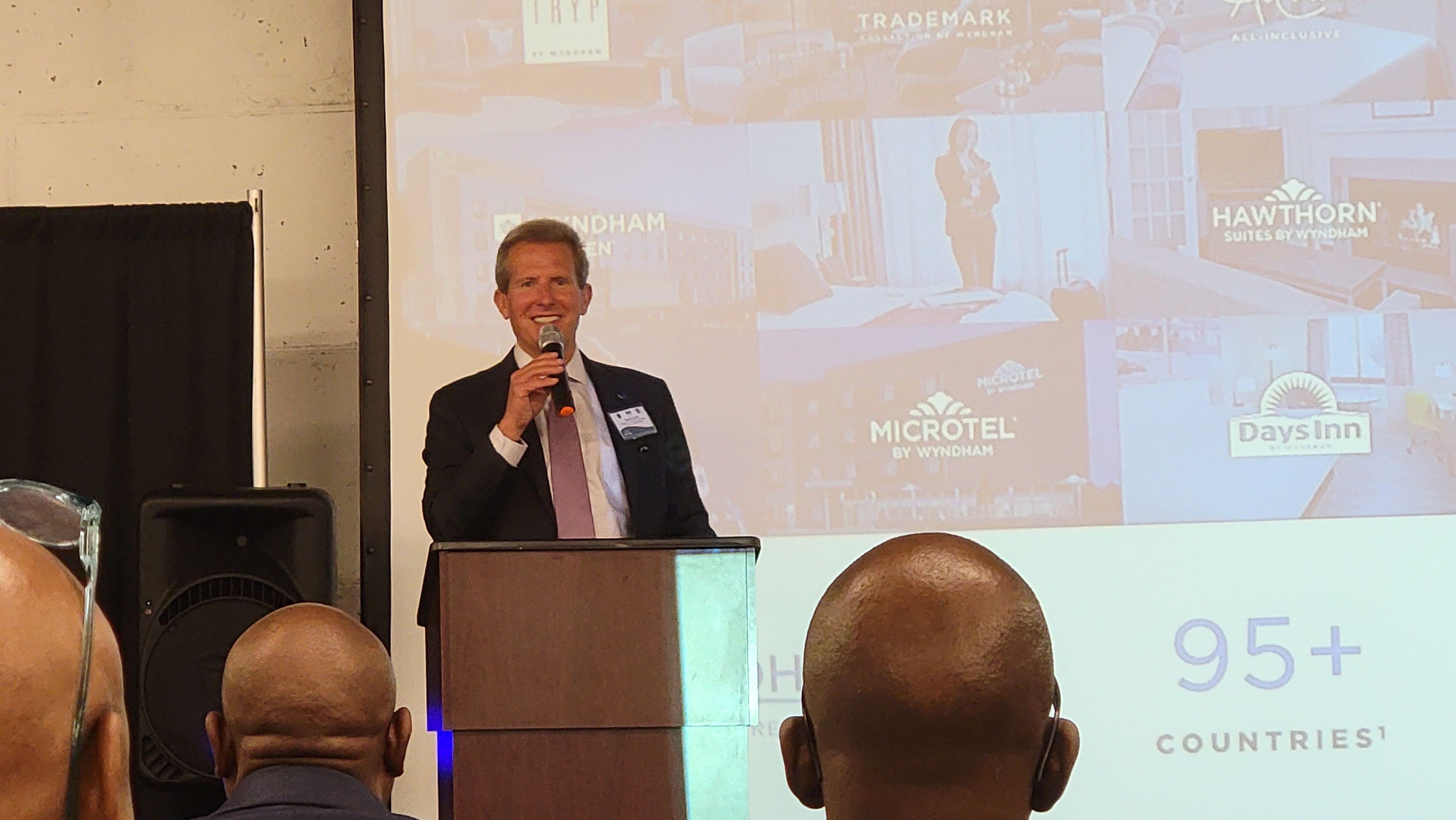 Geoff Ballotti speaking into a microphone at Wyndham's Black Hotel Ownership Symposium in Stonecrest, Georgia