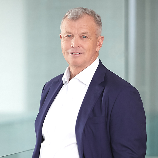 Geoffrey Rehnert wearing an open-collar white shirt and navy jacket