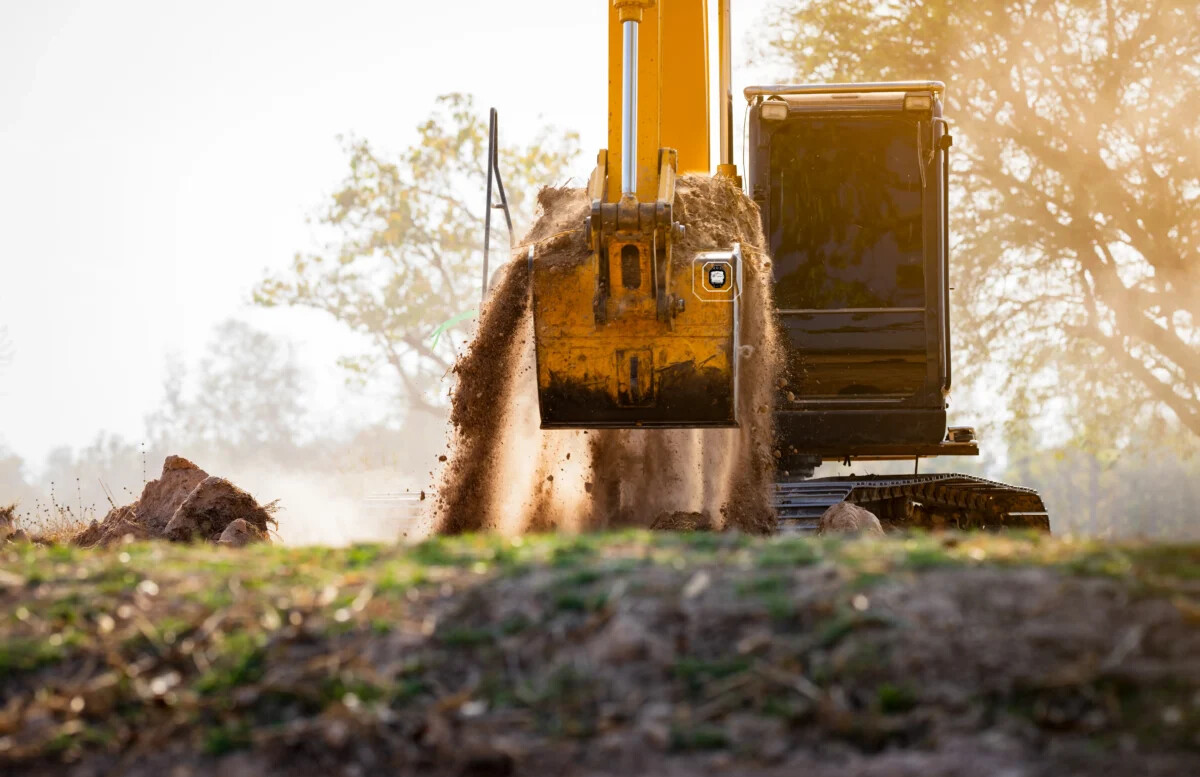 A Geoforce tracker mounted on a yellow excavator bucket as the machine moves soil