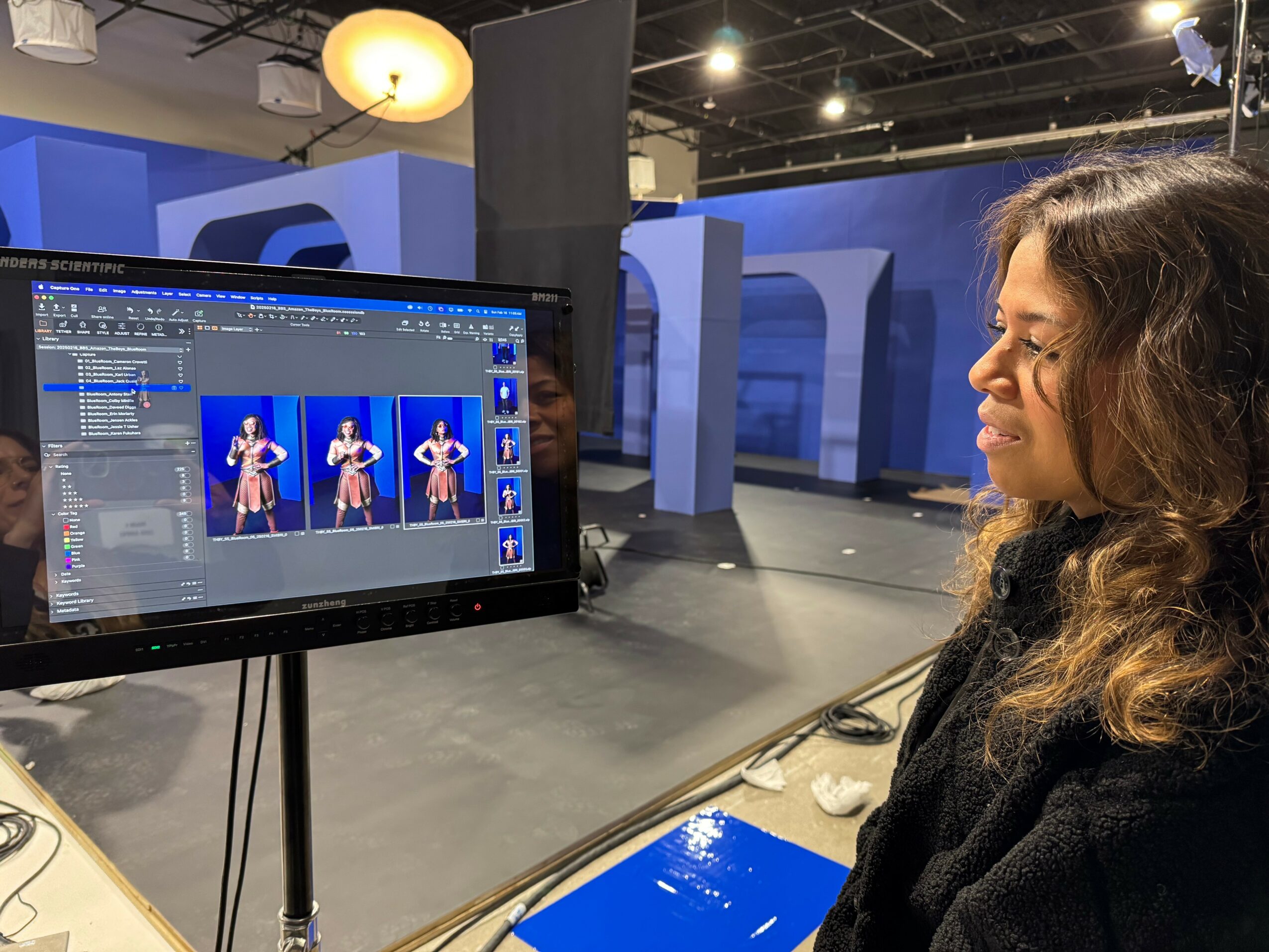 Geonni Sigl reviewing a production image on a monitor beside a blue set