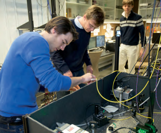 Georg Kucsko, at left, works at a Harvard physics lab bench with Mikhail Lukin and Peter Maurer nearby