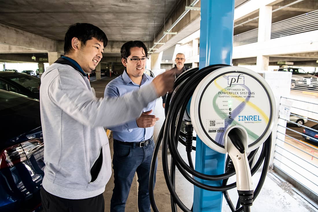 George Lee, at left, working beside a PowerFlex charging station with NREL researchers in a parking garage.