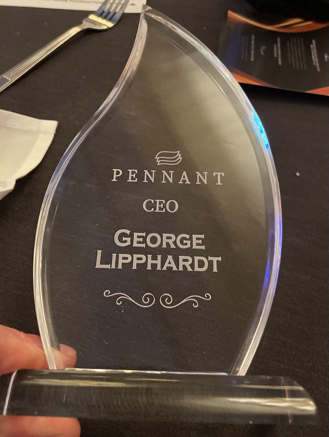 Glass award engraved Pennant CEO George Lipphardt on a banquet table