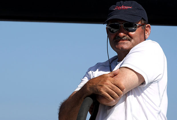 George Sakellaris wearing a Shockwave sailing cap and sunglasses at the yacht’s helm