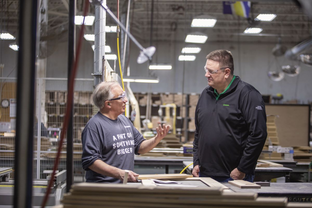 Craig Gorecki speaks with George Wilson beside wood components on the Quanex factory floor