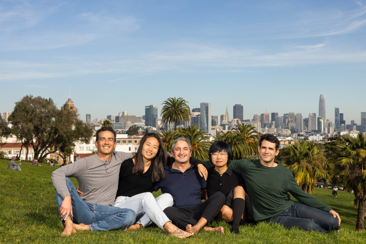 The five humans& co-founders seated together outdoors on a grassy hill
