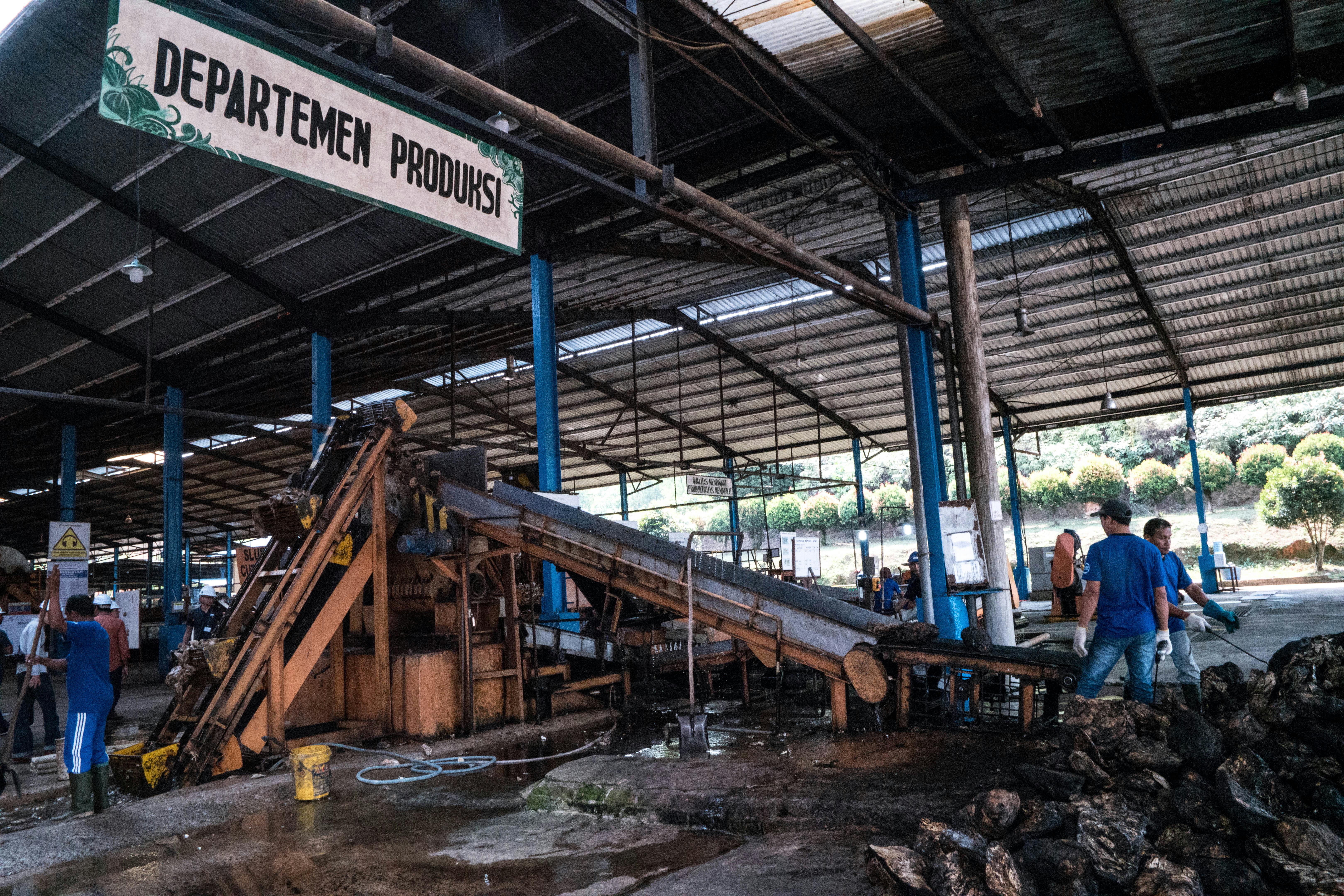 Workers cleaning rubber through machinery at the Pulau Bintan Djaya factory