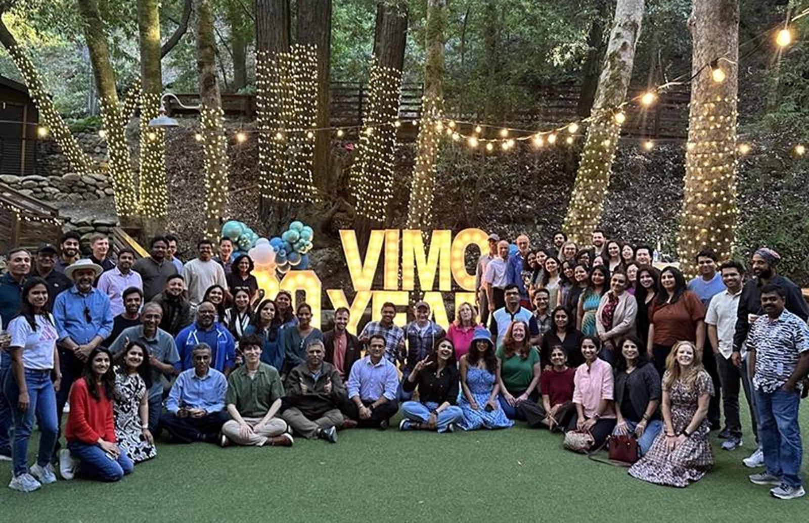 Vimo employees gathered outdoors beneath trees and string lights