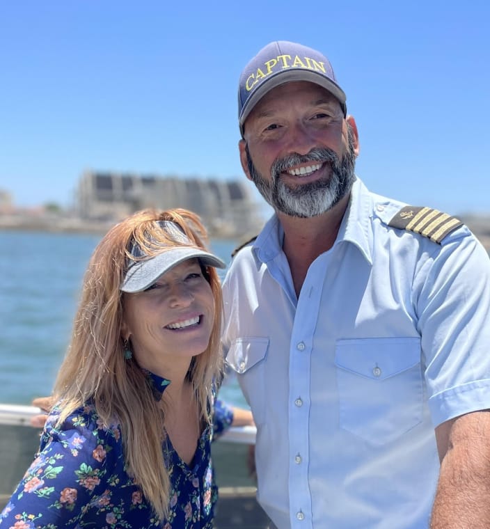 A smiling boat captain with a guest on the water