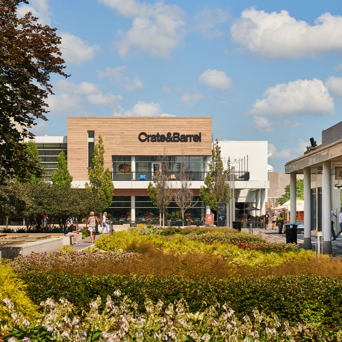 Shoppers outside Crate and Barrel at Oakbrook Center, with landscaped gardens and outdoor walkways