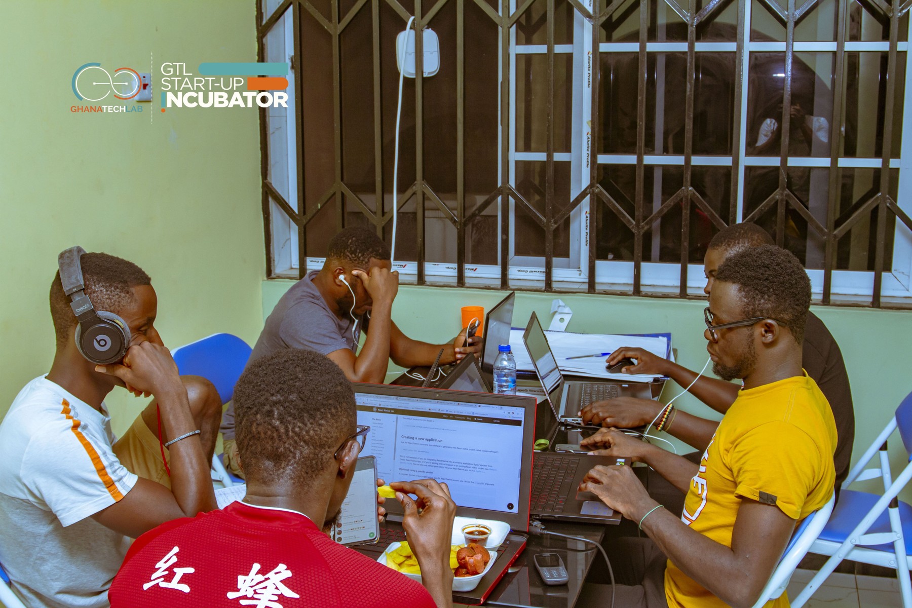 People working on laptops around a shared table at Ghana Tech Lab